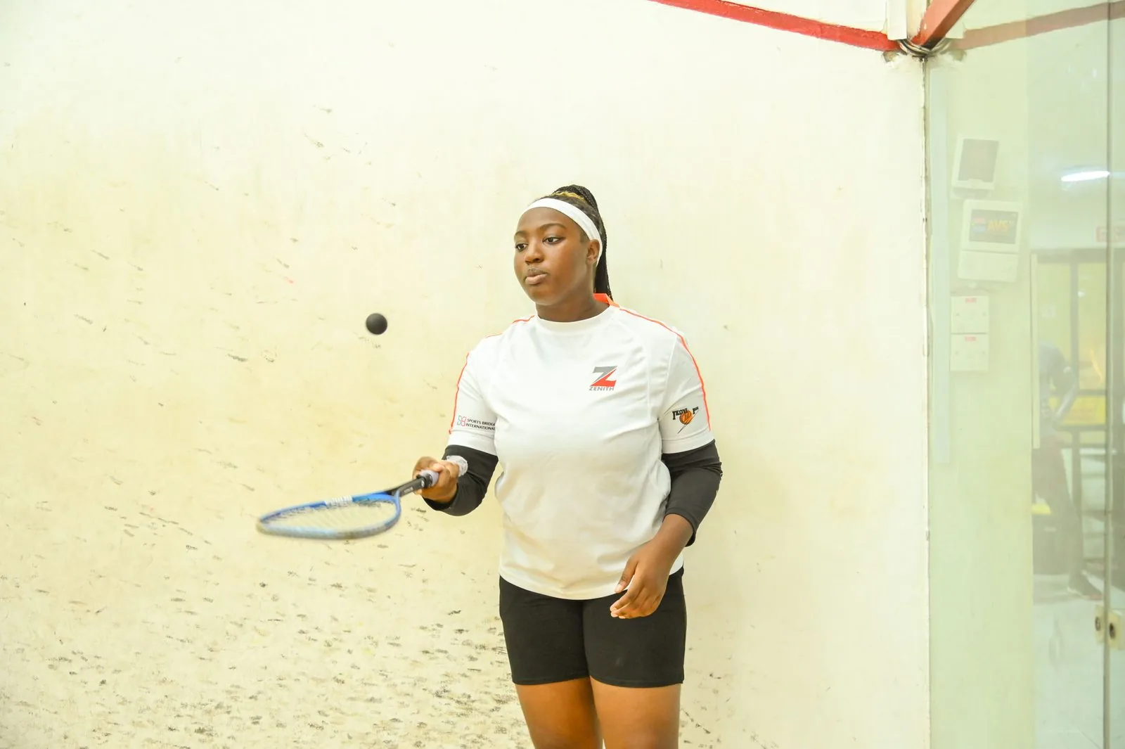 A woman returning a shot on the squash court