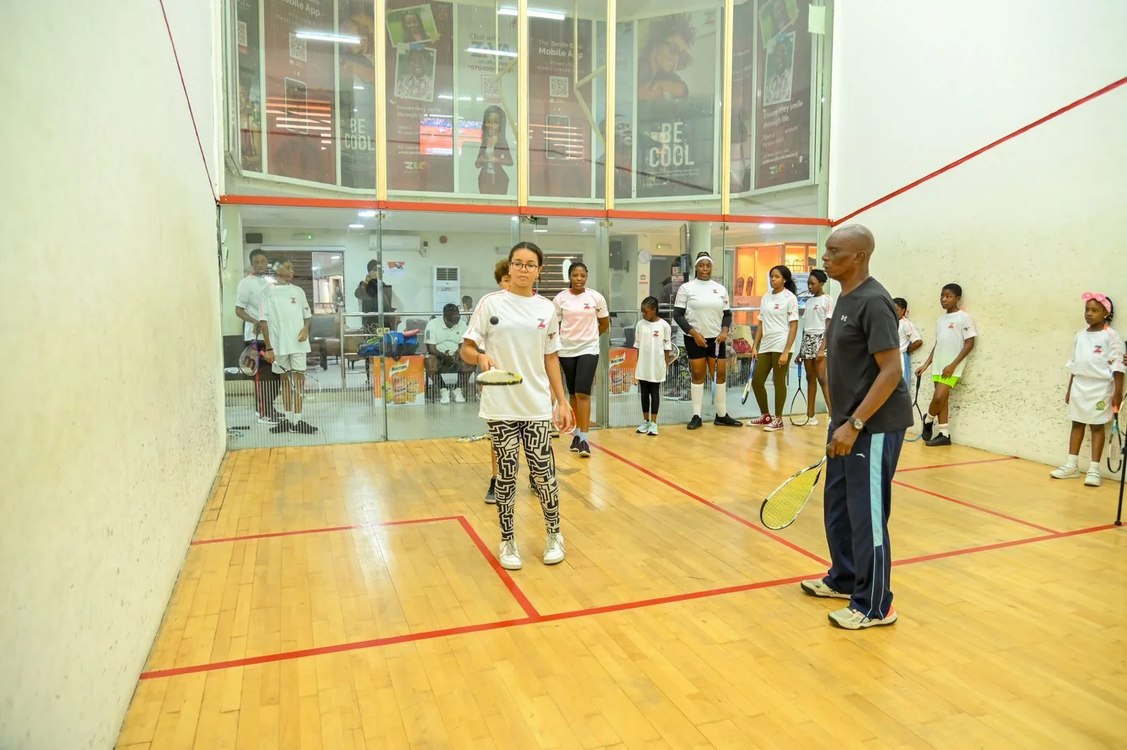 Girls and coaches gathered on the squash court