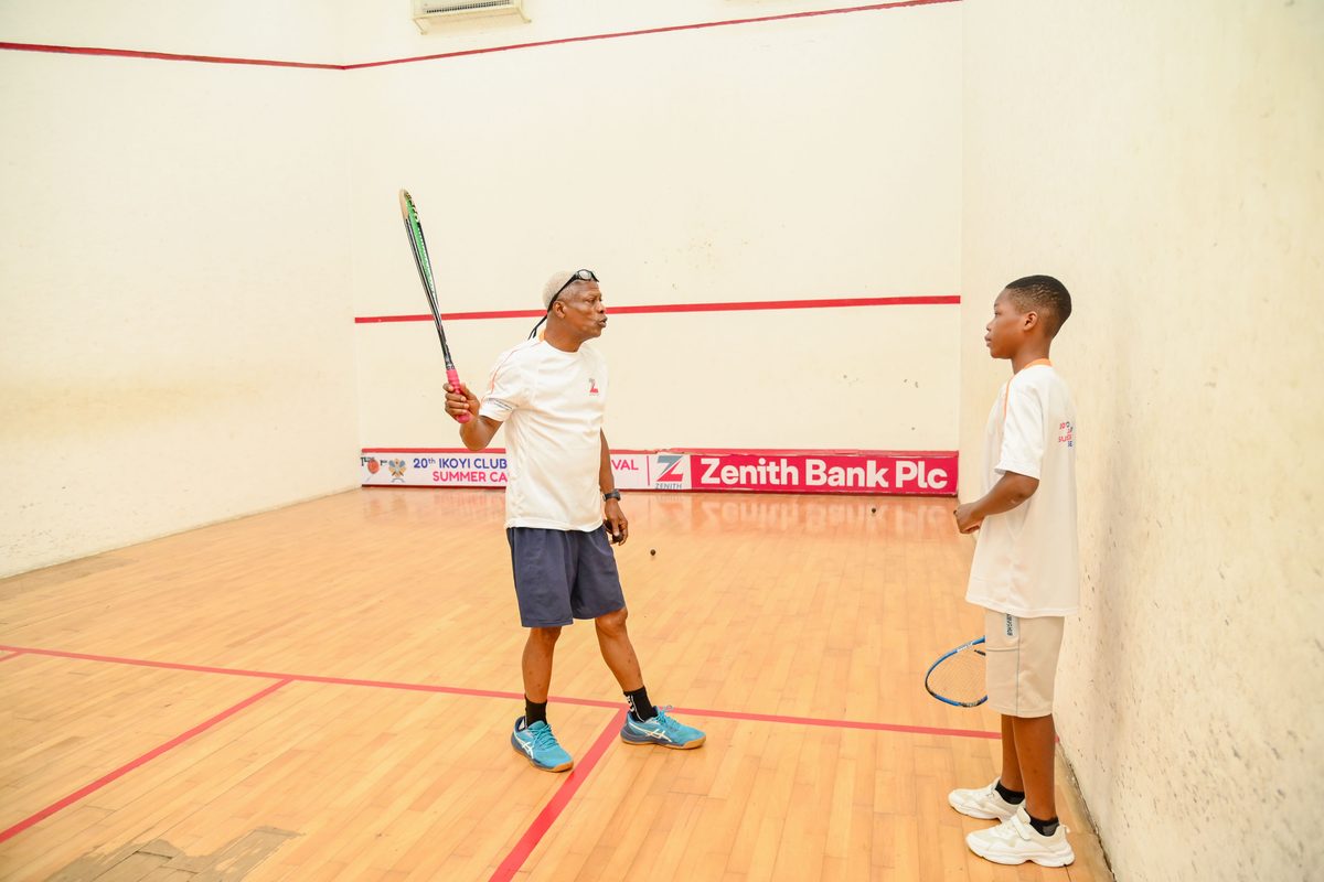 Coach demonstrating racket grip one-on-one to a young male participant at the Ikoyi Club Squashtival Summer Camp