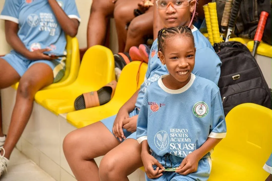A young squash player smiling on the bench between matches