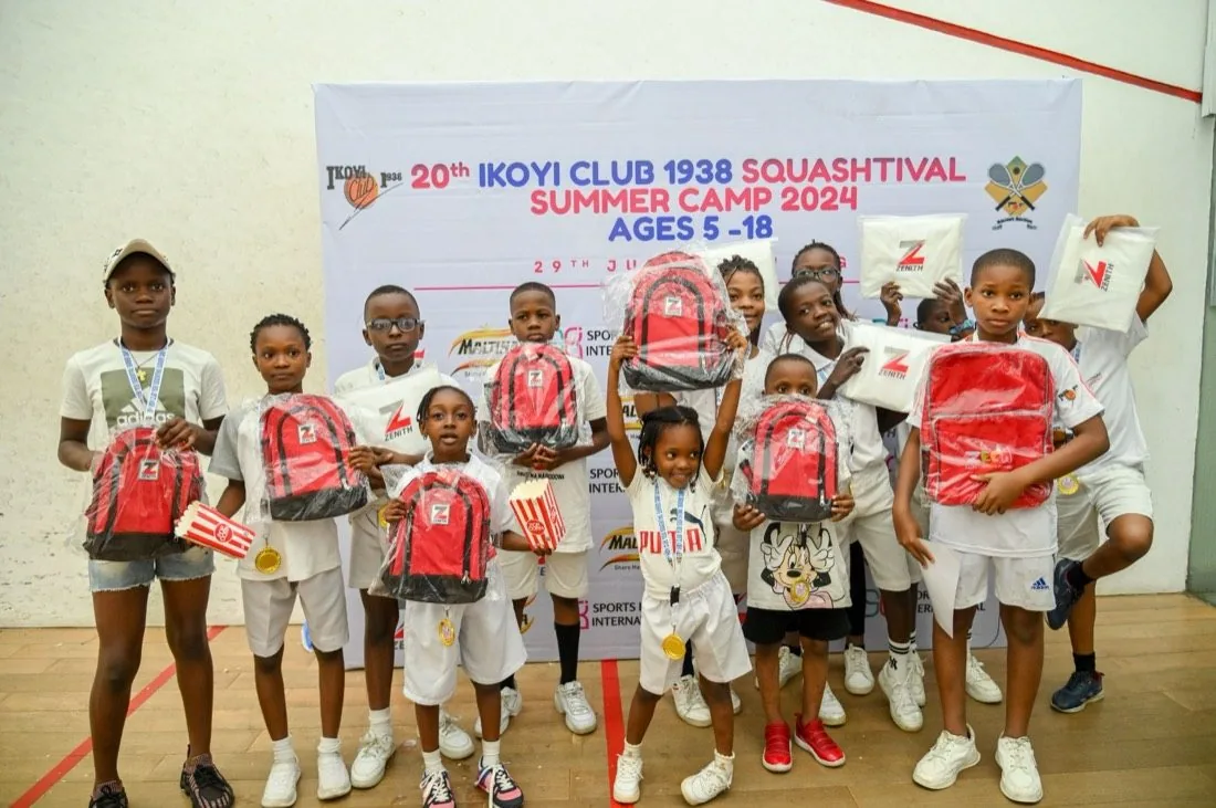 A group of children celebrating with backpacks and prizes at the Ikoyi Club Squashtival summer camp